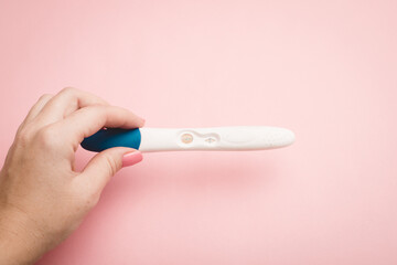 Pregnancy test in hand on a pink background . Positive test. Pregnancy copy space.