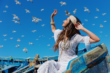 Happy girl looks at the sky and flying seagulls. Essaouira. Morocco - obrazy, fototapety, plakaty