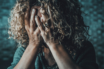 Close up of desperate woman with hands on face in the dark at home. Family gender violence crime...