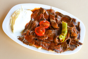 Turkish and Arabic Traditional Ramadan doner kebab with tasty tomato sauce and rice or turkish pilav in white plate on wood table background. ( , Iskender, ekmek arasi pilav ustu doner, doner durum )