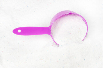 Laundry detergent for washing machines and a plastic scoop for dosing. Washing powder with measuring spoon. White wash powder with with colored granules