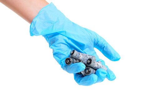 Blue gloved hand holding a bunch of corroded batteries