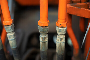 Steel fuel pipes. Tractor parts. Heavy machinery up close. Orange equipment.