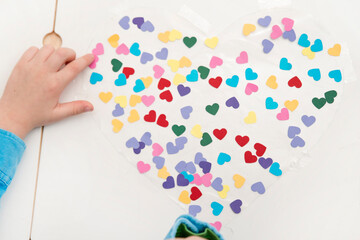 Heart for mothers day. Kid sticking colored paper hearts to adhesive tape. Festive decoration. Woman, Wedding, Happy st Valentines Day concept, 14th February.