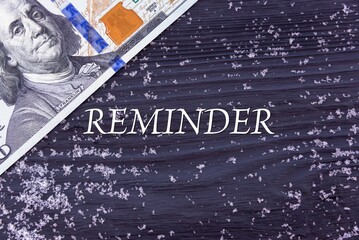 REMINDER - word (text) on a dark wooden background, money, dollars and snow. Business concept (copy space).
