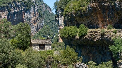 stone building with pitched roof in a large canyon gorge, the Anisclo Canyon, Ordesa National Park, Aragon Spain, blue sky