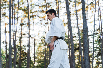 A young guy doing karate training and meditation in the forest during the day