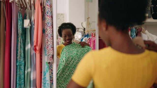 African american woman customer smiling confident holding clothes at clothing store