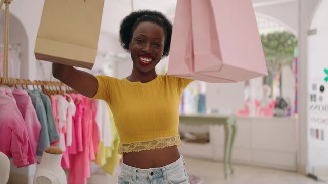 African american woman customer smiling confident holding shopping bags at clothing store