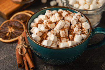 Cup of tasty cocoa drink and marshmallows in blue cup.Spices and marshmallows for winter drinks on black texture table.Winter hot drink.Hot chocolate with marshmallow and spices.Copy space.