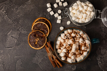 Obraz na płótnie Canvas Cup of tasty cocoa drink and marshmallows in blue cup.Spices and marshmallows for winter drinks on black texture table.Winter hot drink.Hot chocolate with marshmallow and spices.Copy space.