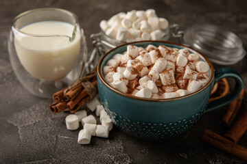 Cup of tasty cocoa drink and marshmallows in blue cup.Spices and marshmallows for winter drinks on black texture table.Winter hot drink.Hot chocolate with marshmallow and spices.Copy space.