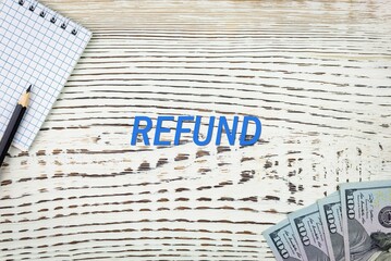 Naklejka premium REFUND - word (text) and dollars on a white wooden table, notebook, notepad. Business concept: buying, selling, commerce (copy space).