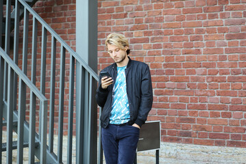 Fototapeta na wymiar Lifestyle portrait of young man using a smartphone outdoors.