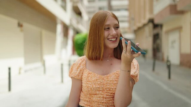 Young redhead woman smiling confident talking on the smartphone walking at street
