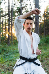 A young guy doing karate training and meditation in the forest during the day