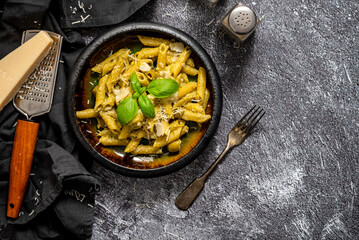 Pasta with parmesan cheese and creamy pesto sauce in black bowl