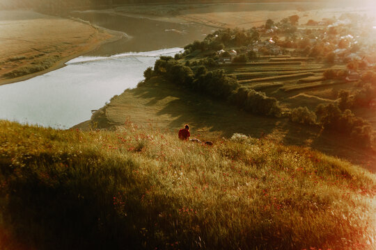 a man is sitting on the bank of the river in the evening