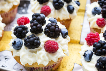 Homemade cupcakes decorated white cream and wild berries, delicious and fresh,