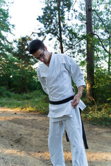 A young guy doing karate training and meditation in the forest during the day