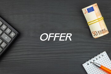 OFFER - word (text) and euro money on a wooden background, calculator, pen and notepad. Business concept (copy space).