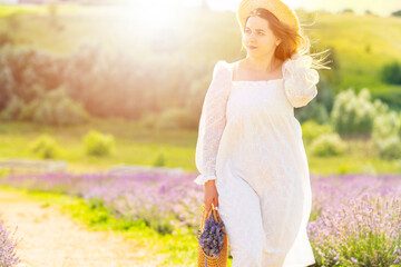 Fototapeta na wymiar Young woman backlit by the sun walking through lavender fields
