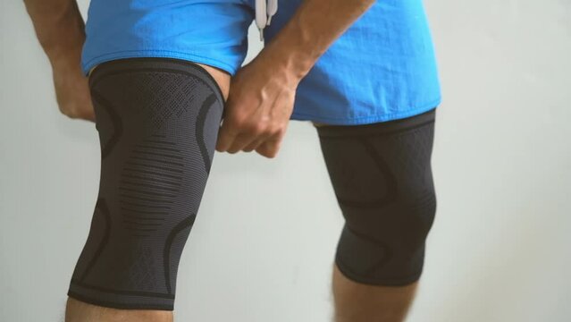 A man puts on a sports knee pad before sports exercises. Arthritis of the knee joint. The concept of joint restoration.
