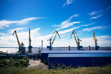 Port cranes against sea, blue sky and white clouds