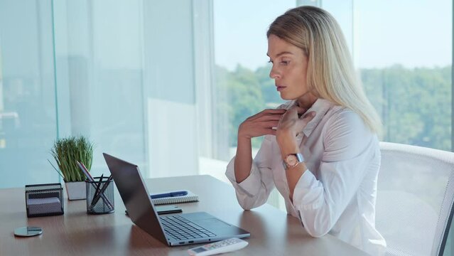 Businesswoman employee feels suffocated working on laptop turn on air conditioner using remote control, cooling system or humidifier. Concentrated woman sets a comfortable temperature Hot summer time.
