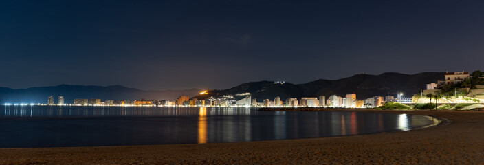 view of a coastal town at night with reflections in the water