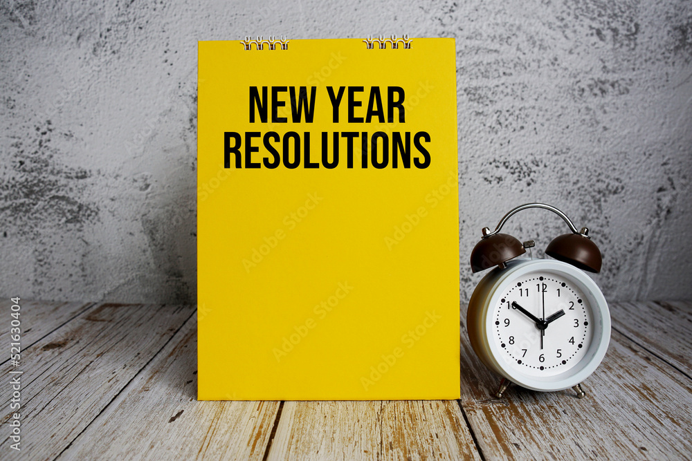 Poster new year resolutions text message and alarm clock on wooden background