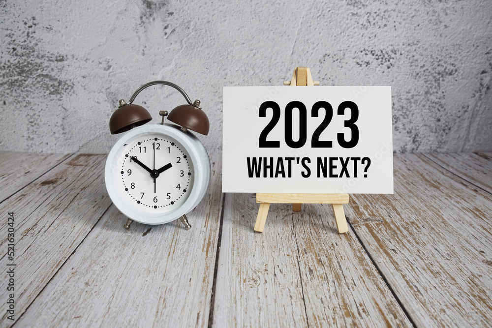 Poster 2023 what's next? text message and alarm clock on wooden background