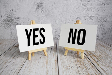 Yes or No text message and alarm clock on wooden background