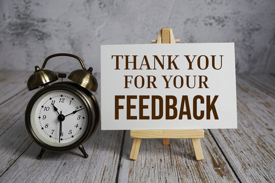 Thank you for your Feedback text message and alarm clock on wooden background