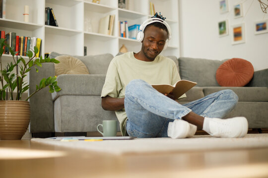  Smart Black Teenage Student In Full Growth With A Book Makes Notes. Smart Teenager Writing Assignment Or Term Paper, Studying Remotely Indoors