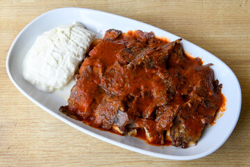 Turkish and Arabic Traditional Ramadan doner kebab with tasty tomato sauce and rice or turkish pilav in white plate on wood table background. ( , Iskender, ekmek arasi pilav ustu doner, doner durum )