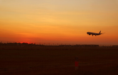 Fototapeta na wymiar Silhouette of an airplane taking off up to golden sunrise sky