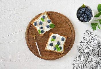 Fresh sweet Blackberry, Blueberry bruschetta, toast with cottage cheese, honey in a white board.