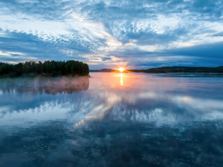 Aerial view of sunset over calm lake during midnight sun in Overtornea, Sweden.