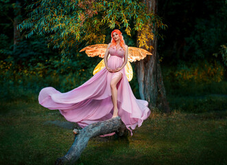 Fototapeta na wymiar Fantasy art portrait red-haired woman fairy sits on log, creative design costume butterfly wings bright glow. Elf girl in orange peach sexy dress. Night dark forest mystic summer nature green trees
