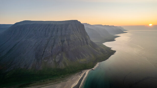 Aerial view of the beautiful coastline with high cliffs and mountain at sunset, Westfjords.