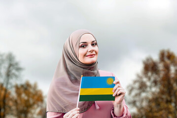 Muslim woman in hijab holds flag of Rwanda
