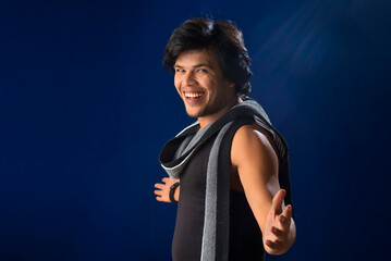 Portrait of a young man posing and showing his muscular body. The concept of a healthy lifestyle on blue background.