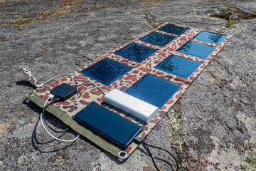 Portable solar panels. Power Bank phone charged by portable solar generator. IVF to phone charging pad. Miniature panels with photoelectric solar traps. Portable power bank. Equipment for ECO tourism - obrazy, fototapety, plakaty