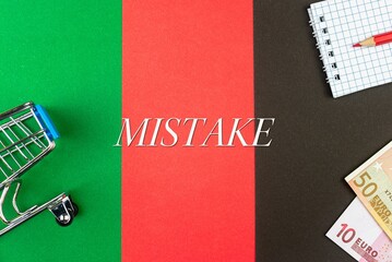 MISTAKE - word (text) and euro money on a table of different colors, a trolley, a basket of grocery notepad and a red pencil. Business concept, buying, selling, supermarket, store (copy space).