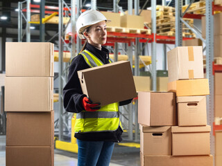 Woman in warehouse. Warehouse worker for courier company. Girl is holding cardboard box....