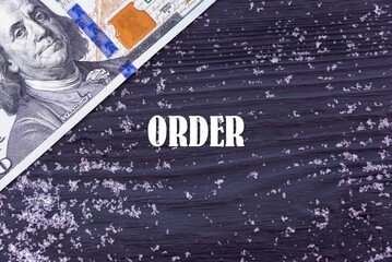 Fototapeta na wymiar ORDER - word (text) on a dark wooden background, money, dollars and snow. Business concept (copy space).