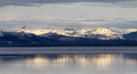 Fototapeta na wymiar View of a frozen Yellowstone Lake with snow covered mountains in American Landscape. Yellowstone National Park. United States. Nature Background.