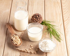 Healthy cedar products milk in glass and bottle, flour, nuts on burlap napkin on wooden table.