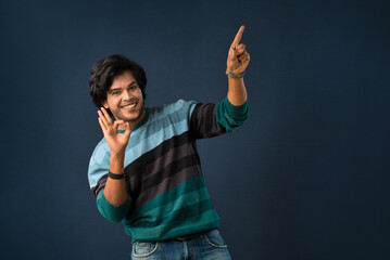 Portrait of a successful cheerful young man pointing and presenting something with hand or finger with a happy smiling face.